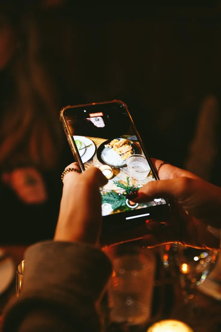 A guest photographing the candlelit table on her phone during dinner
